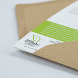 A close-up of Countryside Greetings’ Dick Twinney Know Your Dog Springer Spaniel Greeting Card, partially out of a brown sustainable wood pulp envelope, reveals a document with a green header and Woodland Carbon logo.