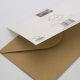 A brown envelope sits beside the CountrysideGreetings Heavy Horse Greeting Card – A5 Size, featuring a stunning draft horse scene by Charles Sainsbury-Plaice with gold logo and green “carbon captured” emblem—ideal for any equine enthusiast.