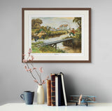 A framed Fly Fishing Print. Tightlines by Thelwell from Countryside Greetings hangs on a gray wall above a shelf with books, a vase of pink flowers, a blue mug, and a model airplane.