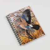 The Autumn Jay A6 lined notebook by Dick Twinney, from Countryside Greetings, features a spiral-bound design with a blue and brown jay among autumn leaves and red berries—ideal for jotting down thoughts.