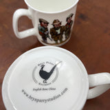 A CountrysideGreetings Bone China Shooting Mug titled Fun Shoot Serious Shoot sits on a wooden surface featuring Bryn Parry outdoor cartoons; another mug is upside down displaying the Bryn Parry Studios logo and website.