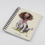 The Cartoon dog themed A6 lined notebook by Countryside Greetings features Bryn Parry’s wide-eyed, happy Springer Spaniel sitting on grass, with “Springer Spaniel” labeled at the bottom of the cover.