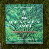 The Queens Green Canopy book by Adrian Houston & Charles Sainsbury-Plaice (SIGNED COPIES, Countryside Greetings) rests on mossy ground with a cover showing sunlight through lush trees and a foreword by His Majesty the King.