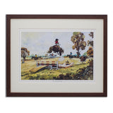 Framed artwork of a horse and rider jumping over a fence in an outdoor setting.